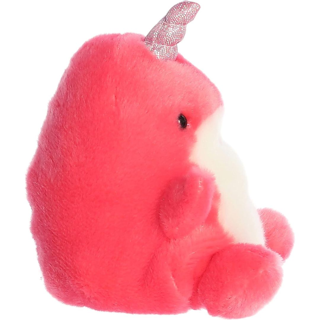 Side profile view of the mini narwhal plush showcasing its rounded hot pink back profile and the upward angle of its metallic horn.