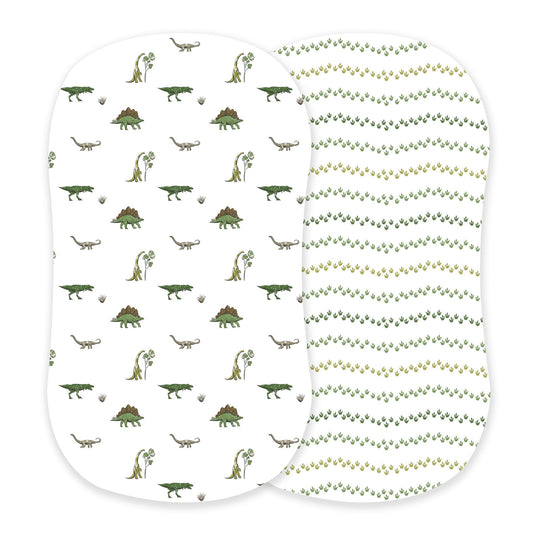 Newcastle Classics two-pack cotton bassinet sheets showcasing the Dino Days dinosaur scene print and green Dino Feet tracks print side-by-side.