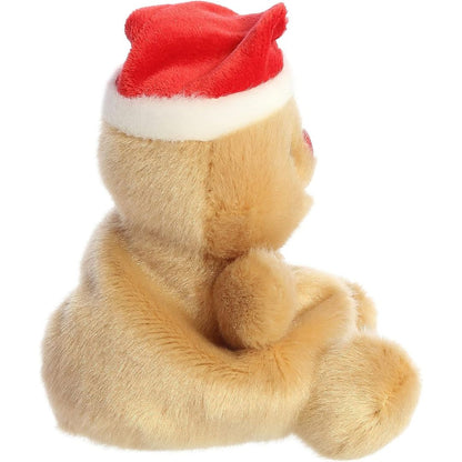 Side profile view thumbnail of the mini gingerbread man plush showcasing its plush seated profile and the red Santa hat sitting on its head.