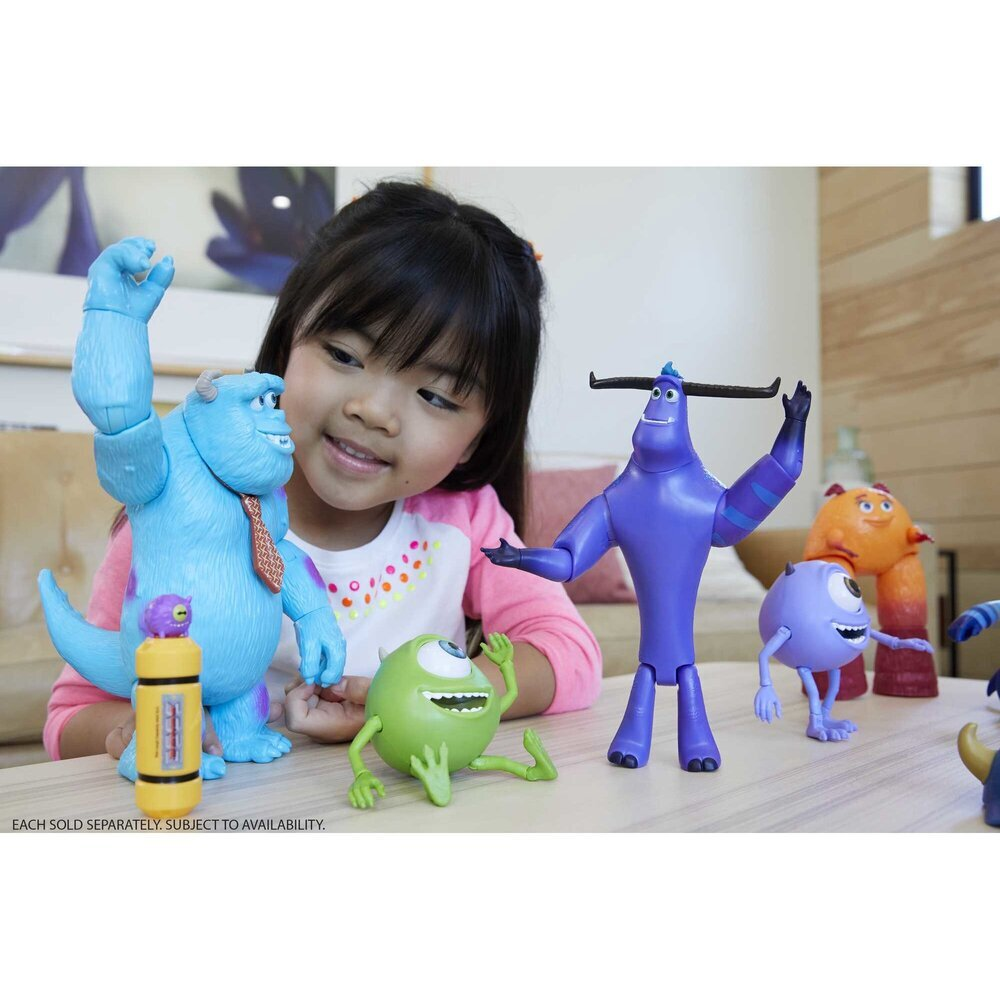 A smiling young girl playing with the posable Tylor Tuskmon action figure alongside a collection of other Monsters at Work character toys.